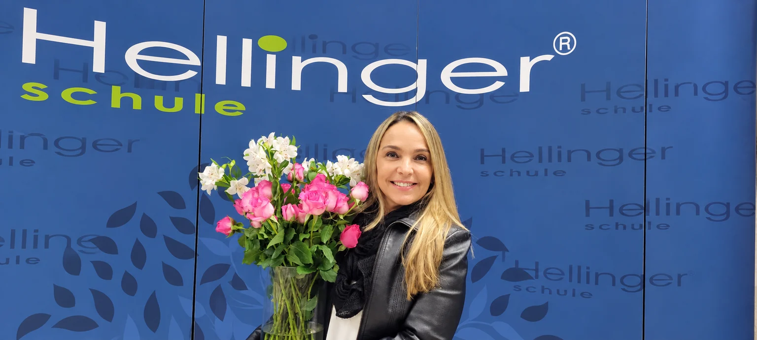 Thais Campos com um buquê de flores na formação da Hellinger®Schule.